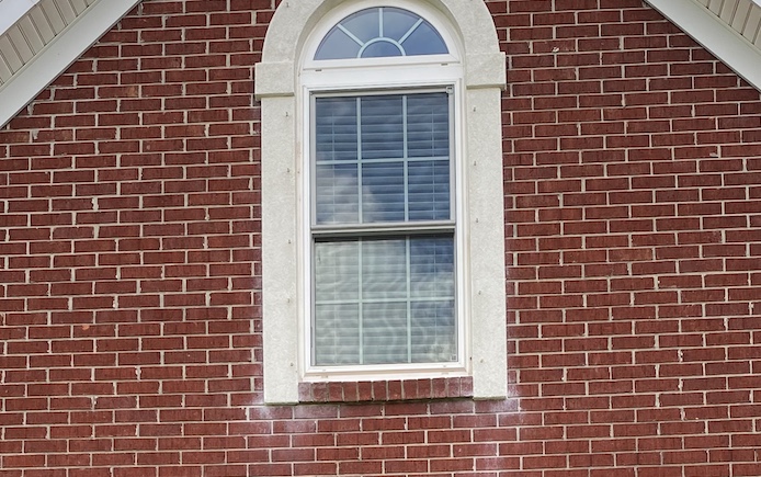 White stains around stucco windows in brick house 