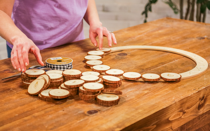 Gluing wood rounds to a floral wreath