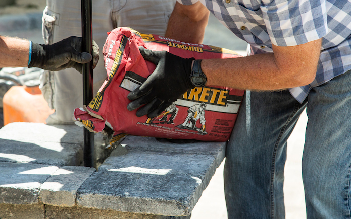 Quikrete fast-setting concrete in the red bag being poured into a paver column.