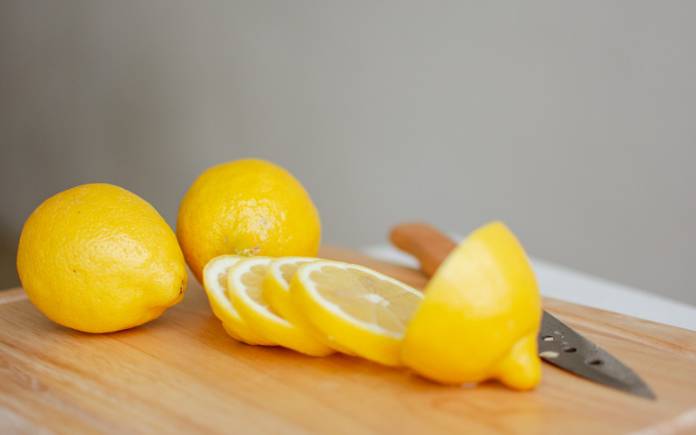 Wood cutting board with whole lemon and slices and knife