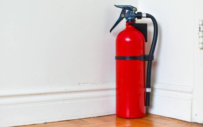 Fire extinguisher against a white wall in a home