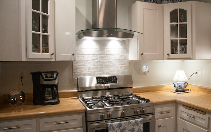 Kitchen stove and range hood with white tile backsplash