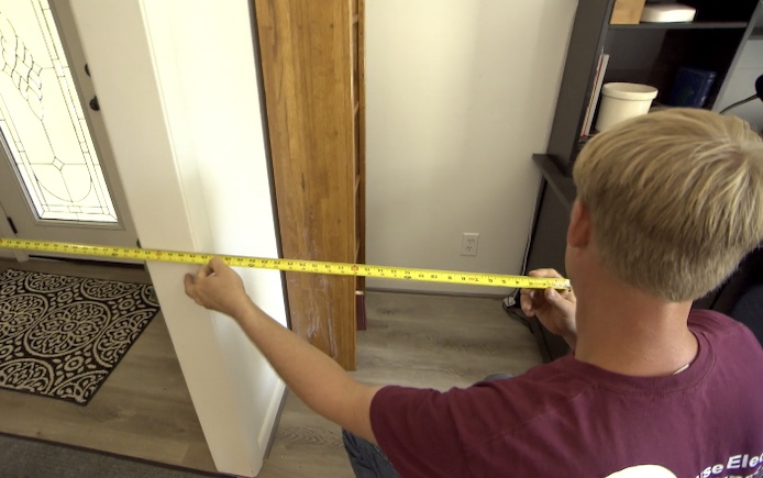 Electrician uses tape measure to find distance from outlet to door