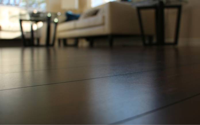 Brown laminate floor with couch and end tables in background