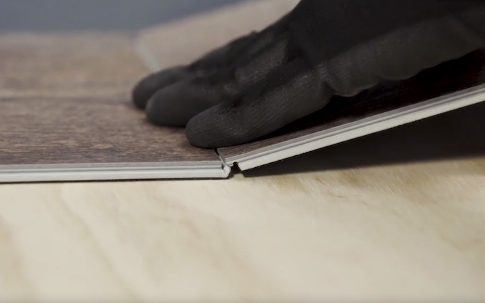 Gloved hand installing Lifeproof waterproof high-traffic luxury vinyl flooring