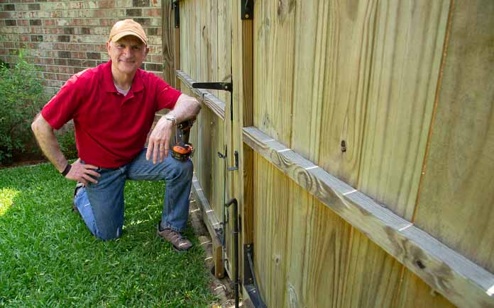 Joe Truini kneels next to a gate with an attahed wooden caster