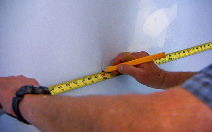 Marking a wall with a pencil and measuring tape
