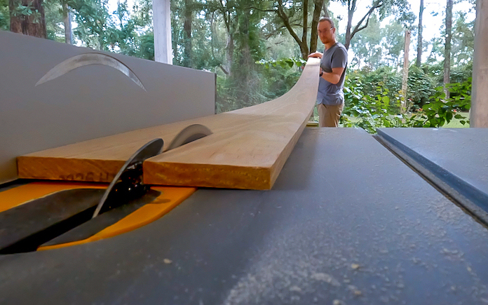 O produtor de rádio de hoje, Corey Wilson, divide uma tábua de pinho em uma serra de mesa. 