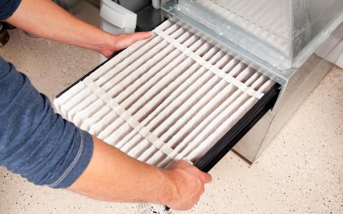 Male hands installing a furnace air filter