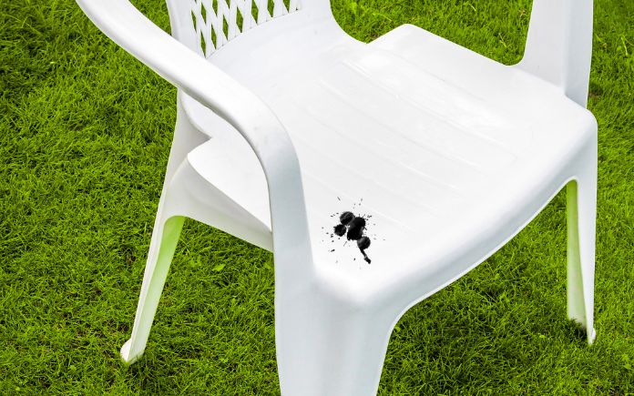Black paint splatter on a white plastic lawn chair