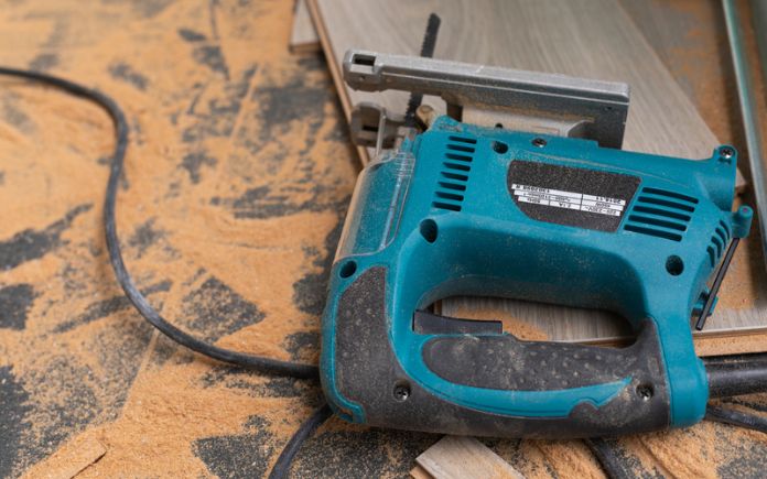 Reciprocating saw on top of laminate flooring with saw dust