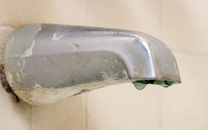 Old bath tub faucet with water dripping