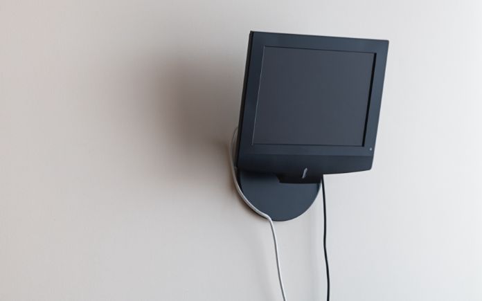 Black TV is mounted on the wall, cables and wires are visible