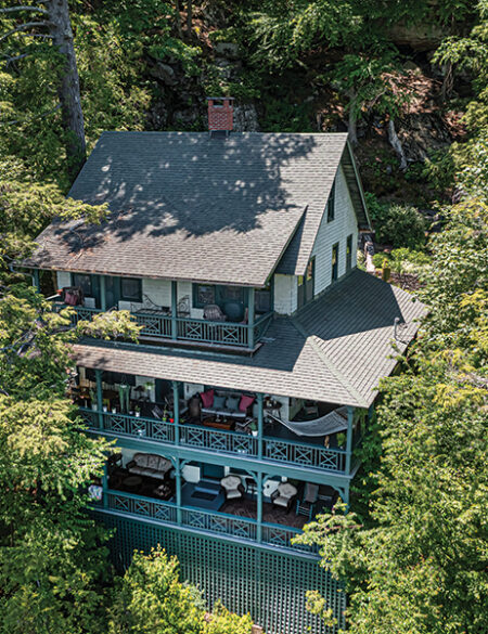 Nestled into the forest, the house extends down a rocky cliff and has porches or balconies on all three levels.
